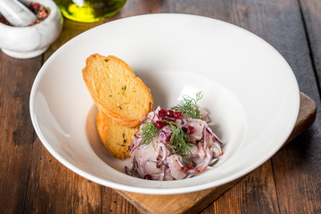 Herring appetizer served with bread in a white plate