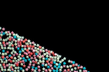 multicolored confectionery sprinkle in the form of stars on a black background