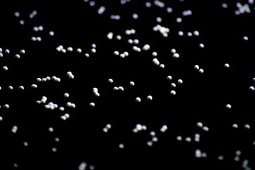 white confectionery sprinkle in the form of balls on a black background