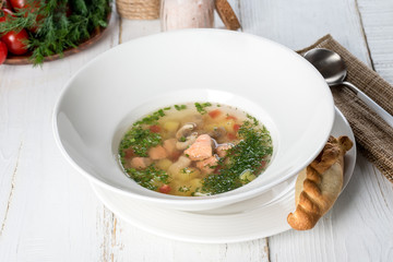 Fish soup with fresh herbs and bread served in a white plate