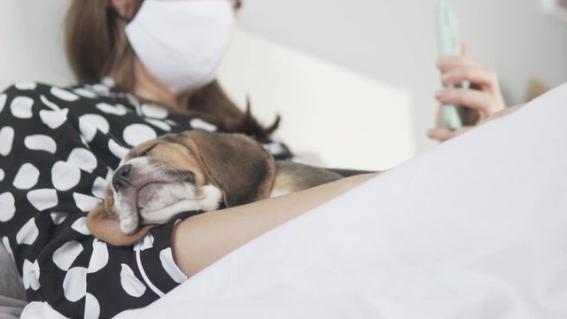 Woman quarantined by coronavirus lies in bed at home with dog