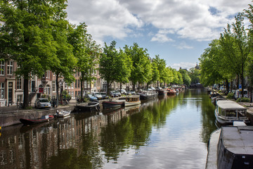 Fluss durch Amsterdam am einem warmen Sommertag mit typischen Booten