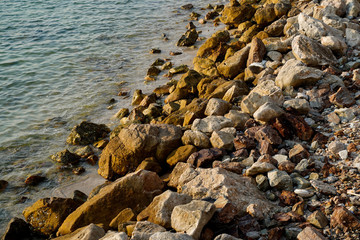 Orange sunset reflction to the rocks on the seashore wild stone beach on coast or shore in Pattaya,Thailand.