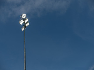 Powerful LED light on a metal pole turned on, cloudy sky background. Concept sport event, game.