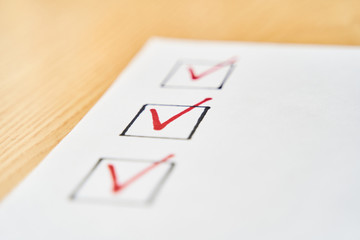 Checklist marked red with a red pen. Close up shot of filled check boxes with red pen