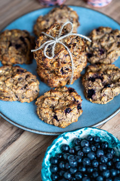Set of easy to prepare and healthy, homemade oatmeal and blueberry cookies - on beautiful blue plate. Bowl full of blueberries next to it.
