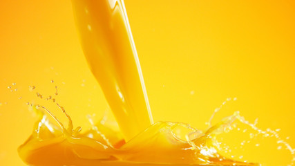 Orange juice splash on coloured background