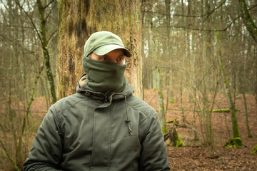 Man with covered face looking into the forest