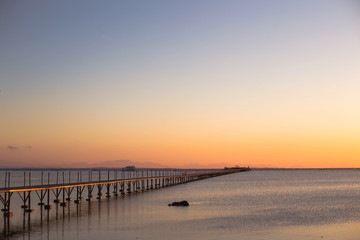 Fototapeta na wymiar a wooden long bridge at the sea at orange sunset,backgound,texture,wallpaper, amazing romantic view, a path for a walk
