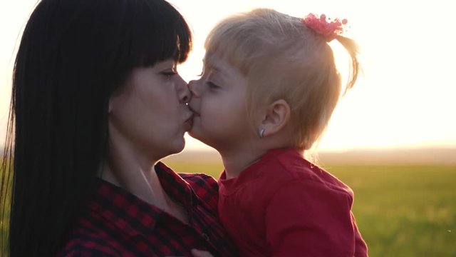 Happy family, mother and child have fun outdoors in the Park. The little lovely blonde girl is having fun and hugs and kisses her mother.