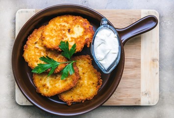 Fresh potato pancakes with sour cream served in a pan, traditional in Polish cuisine