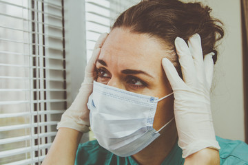 Medical professional in a surgical protective mask is tired after a shift during a coronavirus epidemic.