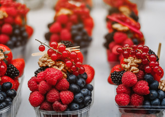 Blueberries, blackberries,raspberry and red currants sold in plastic glass on the street. Street fair. Healthy food nutrition. Charge of vitamins.