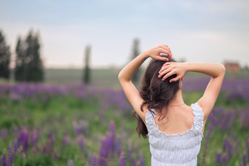 young lady in the field stands with her back