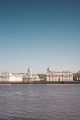 Fototapeta premium Historic university by the blue river with blue sky Vertical