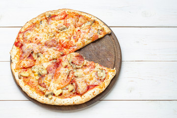 Pizza Francesca with cheese, champignon mushrooms, tomatoes and sliced meat on a white wooden background.