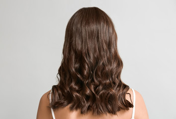 Young woman with beautiful curly hair on grey background