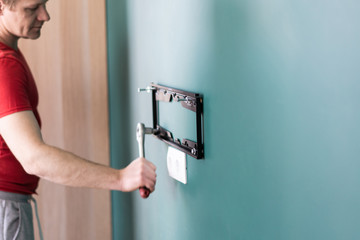 repair and decoration. 'husband for an hour' service. a man attaches a TV mount to a wall.