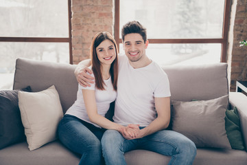 Portrait of her she his he nice attractive lovely cheerful cheery affectionate couple sitting on divan holding hands at modern industrial loft style brick interior living-room flat indoors