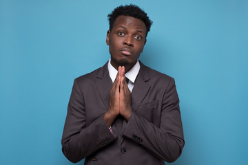Worried african american man in suit put hands together ask for help forgiveness