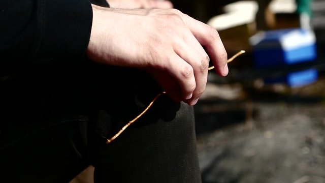 Close up of Male Hand Playing Absentmindedly with a Stick in Camp