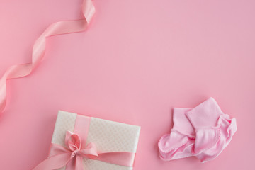 Pair of small baby socks and gift box on pink background. Newborn girl accessories. Postcard, invitation, baby shower. Top view, flat lay, copy space