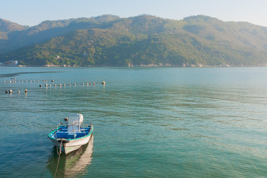 Mui Wo, Silver Mine Bay (Lantau Island, Hong Kong, China). Beautiful landscape with mountains, blue water & sky. Small boat near the shore (Mui Wo Ferry Pier). 