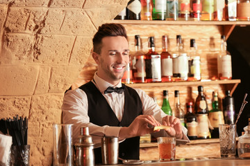 Male bartender making cocktail in pub