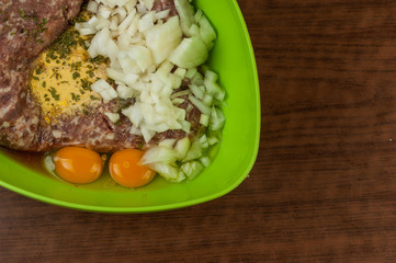 Minced meat in green pot with egg and onion on table.Tasty food