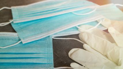 A medical and protective blue mask with white sterile gloves on the dark table as a background. Prevention of Covid-19, virus and other bacterial.