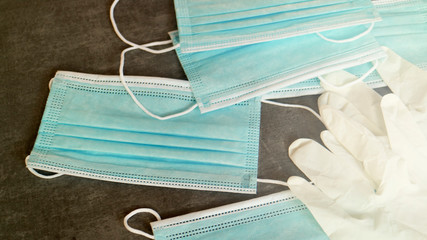 A medical and protective blue mask with white sterile gloves on the dark table as a background. Prevention of Covid-19, virus and other bacterial.