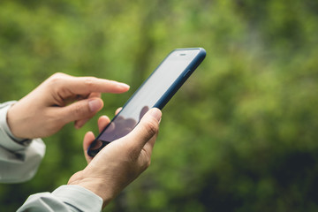 Hands using mobile phone in spring nature