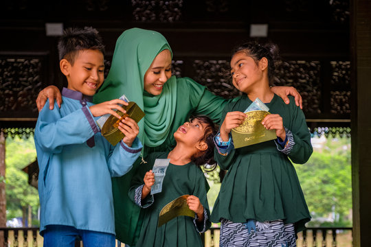 Happy Children Holding An Envelope Of Pocket Money Or Raya Angpao From Their Mother During Eid Al-Fitr Celebration. Malaysian Family And Raya Concept.