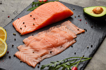 Fresh sliced salmon fillet with arugula, avocado and lemon on slate plate. Wild atlantic fish