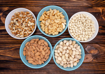 Dried variety of nuts into a bowl on wooden background. Healthy food