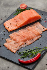 Fresh sliced salmon fillet with arugula, avocado and lemon on slate plate. Wild atlantic fish