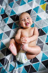 little boy age 8 months and is smiling. He wears a diaper. Health and development of children