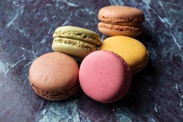 Aerial view of colored macarons, with selective focus, on blue marble and horizontal with copy space