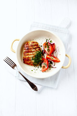 Grilled Turkey Breast with tomatoe salad. White wooden background. Top view. 