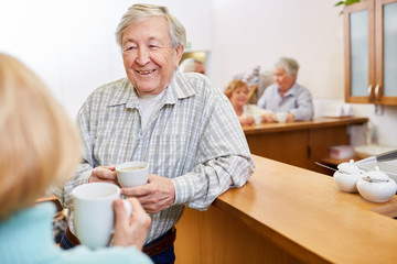 Zufriedener Senior Mann beim Smalltalk bei einer Tasse Kaffee im Seniorenheim