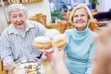 Senioren im Altersheim essen Berliner Pfannkuchen und trinken Kaffee zusammen