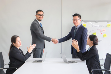 Business people shake hands after reaching a business agreement with a secretary sitting and...