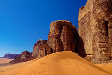 WADI RUM DESERT, JORDAN - FEBRUARY 06, 2020: Sand dunes in the foot of the giant red rocks of Jebel...