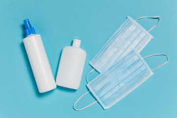 Coronavirus protection. Medical surgical masks and bottles of disinfectant and alcohol hand sanitizer on blue background. Hygiene measures to prevent spread of Covid-19 pandemic
