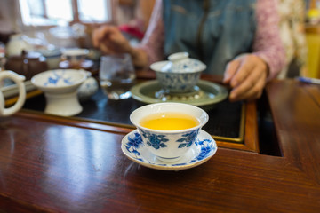 Porcelain tea cup with beautiful blue patterns. Filled with Pu Erh tea, gung fu cha style. Blurred background. 