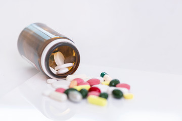Pills scattered on a white background in different colors and shapes. World coronavirus pandemic. Close-up. Flare. Space for text.