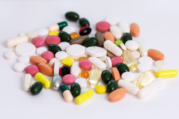 Pills scattered on a white isolated background in different colors and shapes. World coronavirus pandemic. Close-up.