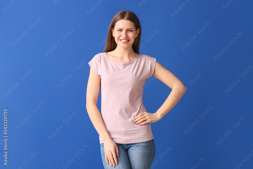 Wall mural young woman in stylish t-shirt on color background