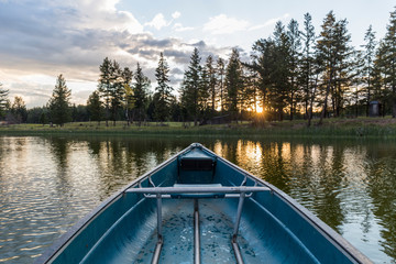 closeup of the bow of a blue canoe on a lake at sunset