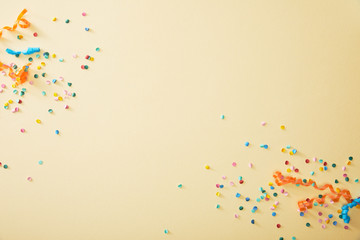 Top view of festive colorful confetti on beige background - obrazy, fototapety, plakaty